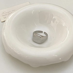 Detailed close-up of a silver square signet ring with a polished mirror finish surface