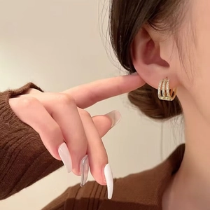 Elegant gold earrings with triple rows of micro-paved cubic zirconia on model