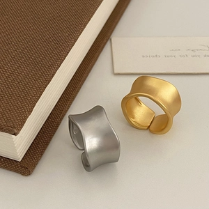 Macro view of matte gold and silver rings with irregular wavy edges and brushed finish
