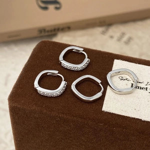Vue macro de boucles d'oreilles créoles carrées en argent avec détails en zircon pavé
