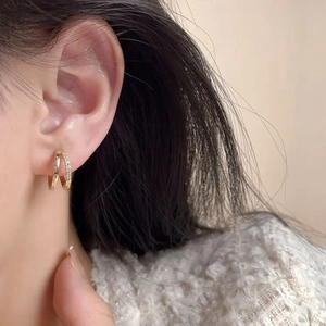 Close-up of double-hoop gold earrings with pavé cubic zirconia on the earlobe