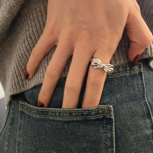 Silver bow-shaped open ring with elegant ribbon fold design shown on hand