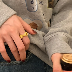 Close-up of a polished gold bow ring worn on a finger for a chic, minimalist look