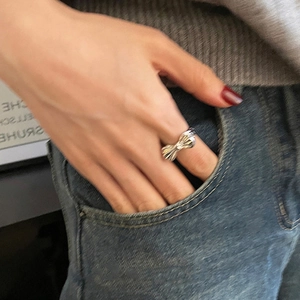 Close-up of silver bow-shaped open ring worn on a finger for a stylish casual look
