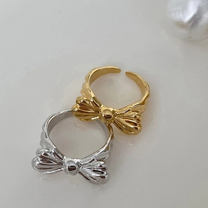 Close-up of gold and silver bow-shaped open rings with elegant wavy band texture
