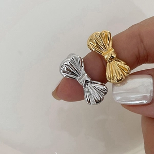 Close-up of elegant gold and silver bow-shaped open rings worn on model fingers