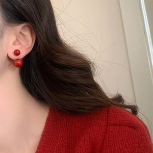 Macro side view of elegant red double pearl earrings with glossy finish on model