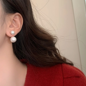 Close-up of elegant double pearl earrings featuring large and small beads on a model