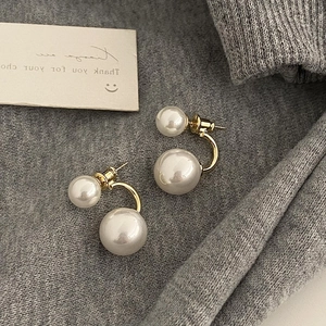 Detail view of French-style double pearl earrings with gold U-shaped metal studs