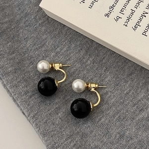 Detail view of two-way pearl earrings with black and white pearls on gold U-shape alloy
