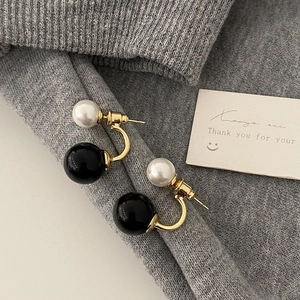 Detail of French minimalist stud earrings with gold metal and contrast black and white beads