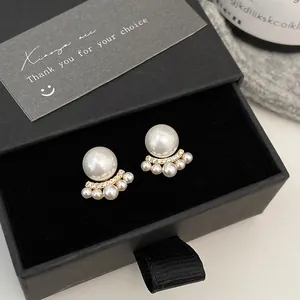 Detail of French cat claw pearl earrings on black velvet padding with gold finish