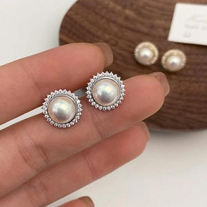 Macro close-up of French style pearl stud earrings with sparkling sunflower halo