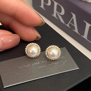 Detail of French style pearl earrings with gold base and zircon sunflower halo