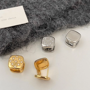 Macro shot of gold and silver square hoop earrings with star-set zircon and plain finish