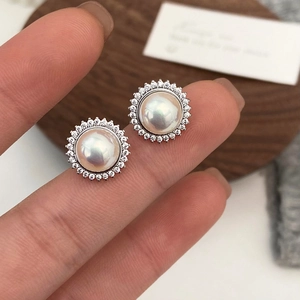 Macro shot of French style pearl stud earrings with sparkling halo zircon setting