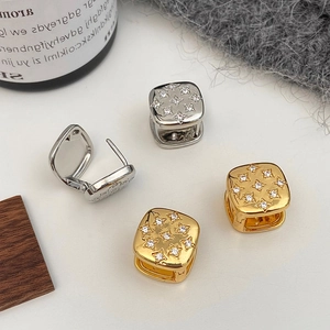 Detailed view of gold and silver square hoop earrings with star patterns and zircons