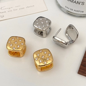 Detail of square gold and silver earrings with star pattern zircon micro-inlay