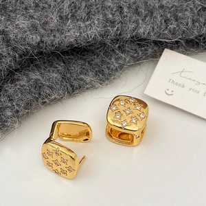 Macro view of gold-plated square stud earrings with star pattern and zircon inlay