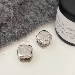 Macro detail of silver square hoop earrings with sparkling zircon starburst patterns