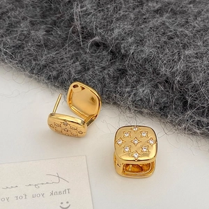 Macro shot of 18K gold square hoop earrings with micro-inlaid star-shaped zircons