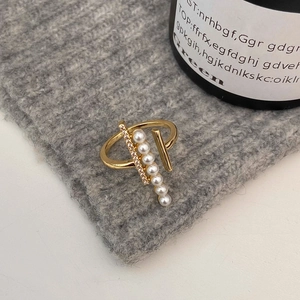 Detail of geometric gold ring with pearls and zircons on grey knit fabric