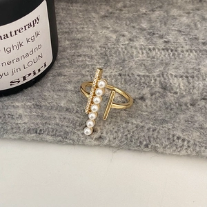 Detailed macro of gold ring with parallel rows of pearls and zircon on gray fabric