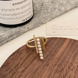 Macro view of 18K gold pearl and zircon ring on a walnut display stand with soft light