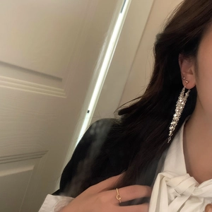 Close-up of elegant long silver tassel earrings worn by a model in casual attire