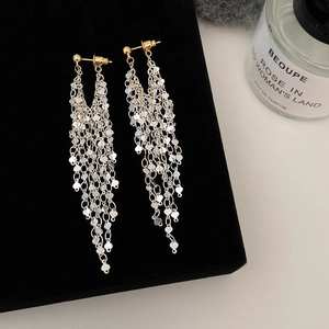 Macro shot of long silver tassel earrings with heart pendants on a black velvet stand