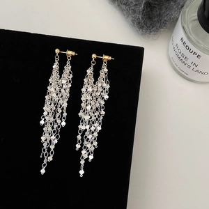 Macro detail of silver long tassel earrings with heart pendants on black velvet stand