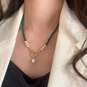 Detail of freshwater pearl and green stone necklace with a gold clasp and pearl pendant