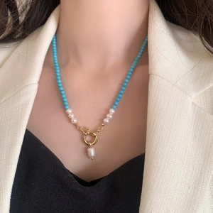 Detail of freshwater pearl and turquoise necklace with a baroque pendant on a model