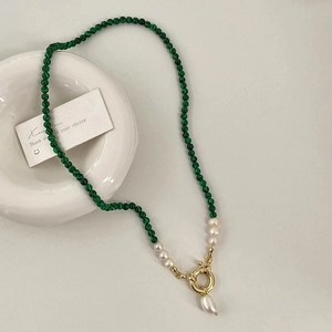 Detail of freshwater pearl and green malachite beaded necklace with a golden toggle clasp