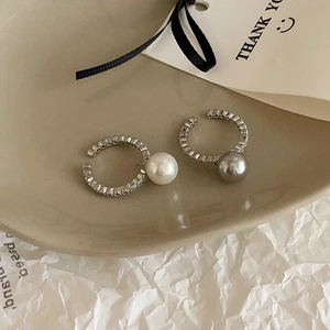 Detail of silver pearl ear cuffs with clear cubic zirconia on a ceramic tray