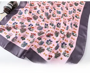 Detailed view of pink floral silk scarf with orange chain pattern and purple border