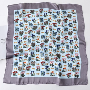 Detail of silk square scarf with floral prints and golden chain motifs on blue fabric