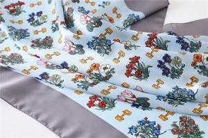 Detail of light blue silk scarf with equestrian horsebit and floral print patterns