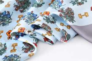 Detailed close-up of a blue silk scarf featuring vibrant floral and horse bit patterns