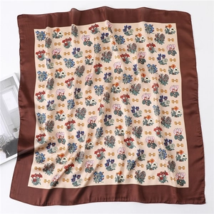 Close-up of square silk scarf featuring floral prints and golden horsebit patterns