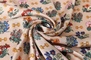 Detailed close-up of champagne silk fabric with vibrant floral and horsebit patterns