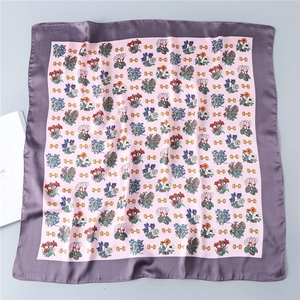 Macro detail of square silk scarf with floral prints and horsebit pattern on satin fabric