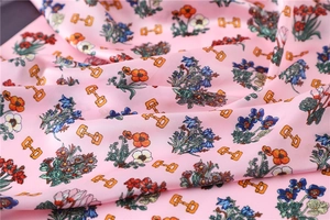 Detailed macro view of soft pink silk-like fabric with floral and horse-bit print patterns