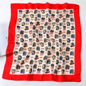 Flat lay of silk scarf with floral patterns, gold chain motifs and red borders