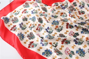 Detail of silk scarf with floral horse bit print and elegant red border accent