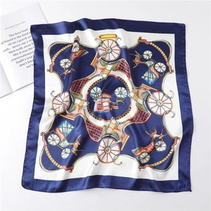 Flat lay of silk scarf with navy blue edge and vintage horse carriage pattern and gold chains