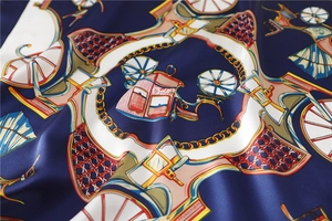 Detailed view of navy blue silk scarf with vintage carriage and gold chain patterns