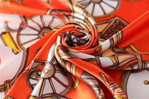 Macro shot of orange silk scarf showing baroque wheel patterns and smooth texture