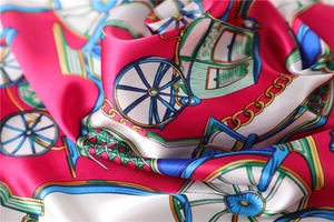 Close-up of square silk scarf showing glossy texture and vintage horse carriage pattern