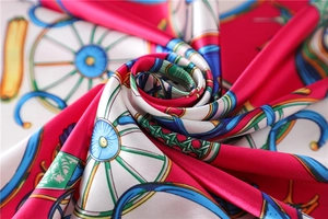 Macro shot of silk scarf with equestrian horse carriage wheel print in bright red